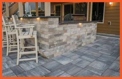 Outdoor patio setup with stone bar and high chairs under string lights at Summit Liquidations – Mountain City.