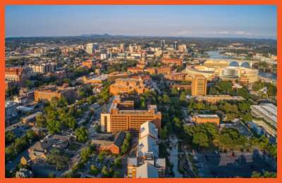 Aerial view of a vibrant cityscape with stadiums, downtown buildings, and lush greenery at sunset, representing the region around Dollar Days Treasure Hunt – Pikeville.